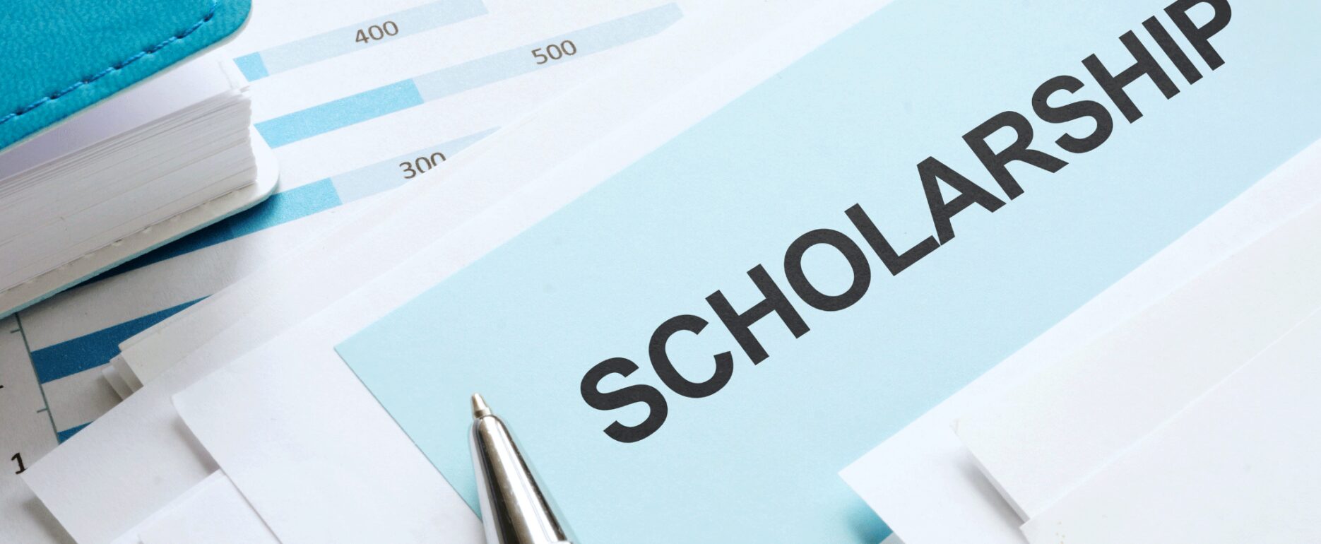 an image of stacks of paper with the word SCHOLARSHIP and a pen indicating study abroad scholarships