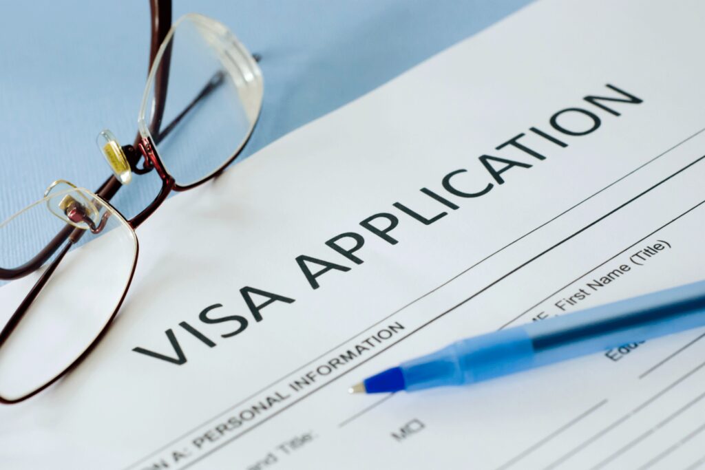 An image for a Visa Application with a blue ballpen and a red frameless eyeglasses