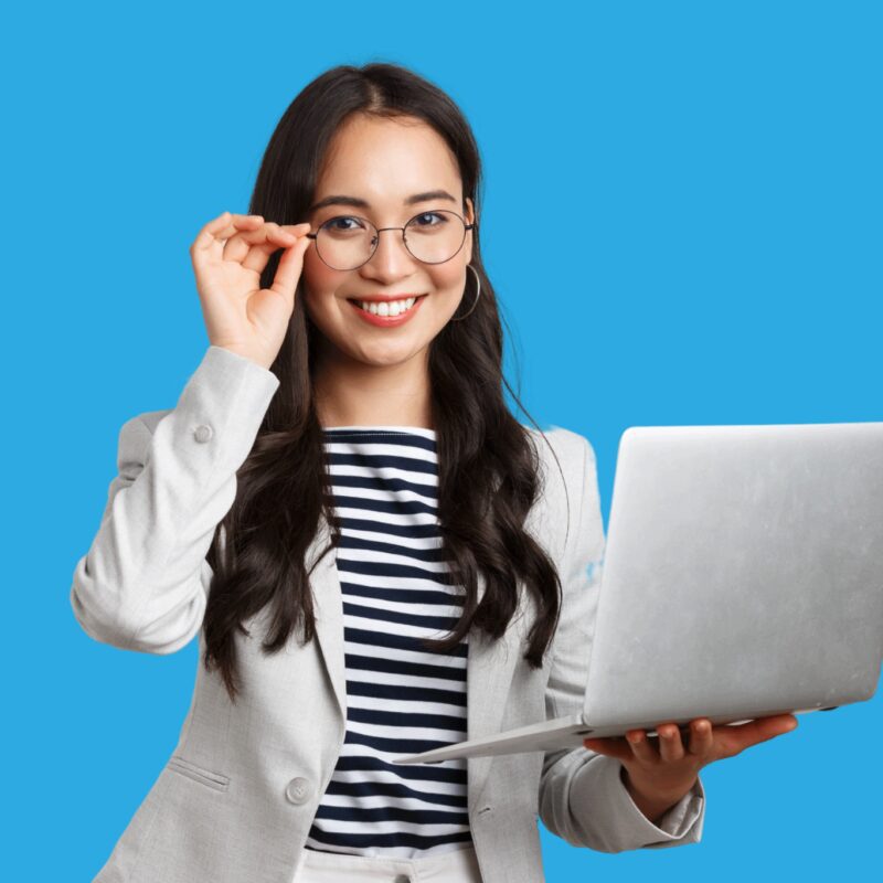 A councilor for study abroad assessment, A standing smiling girl holding her eye glasses using her right hand and her laptop on her left hand on a blue background